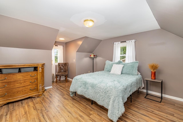 bedroom featuring vaulted ceiling, wood finished floors, baseboards, multiple windows, and recessed lighting