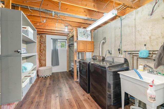 laundry area featuring independent washer and dryer, light wood finished floors, and a sink