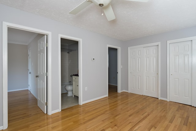 335 Fernwood Dr, Williamstown, KY 41097 - unfurnished bedroom with light wood-style floors, multiple closets, baseboards, a textured ceiling, and connected bathroom