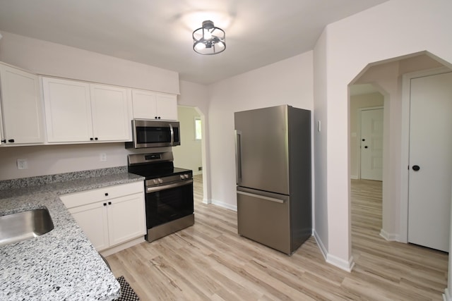 529 Stevenson Rd, Erlanger, KY 41018 - kitchen featuring stainless steel appliances, arched walkways, white cabinetry, and light wood finished floors