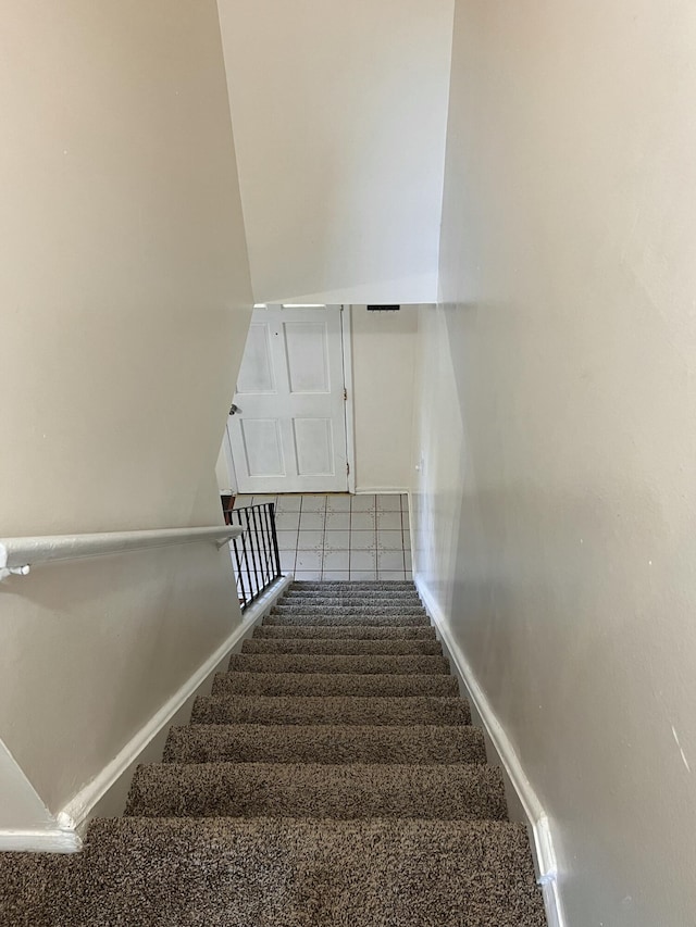 staircase featuring baseboards and carpet flooring