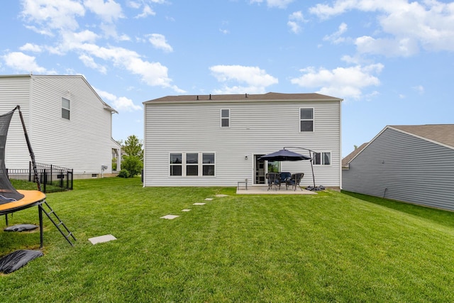 rear view of property with a trampoline, a patio, and a lawn