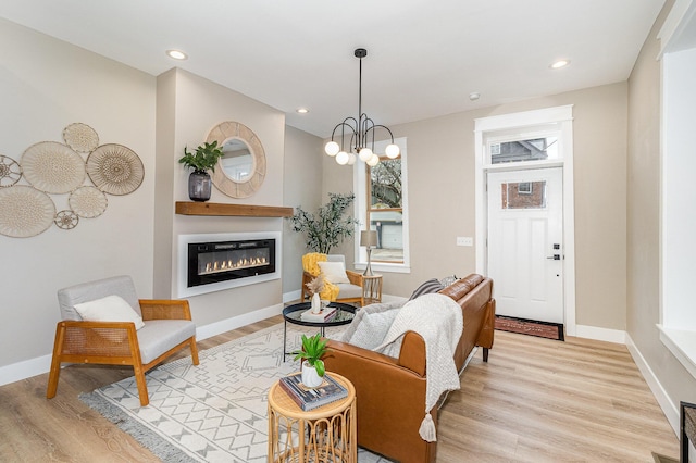 1102 Lee St, Covington, KY 41011 - living room featuring light wood-type flooring, a glass covered fireplace, a chandelier, baseboards, and recessed lighting