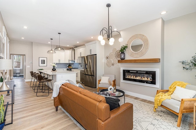 1102 Lee St, Covington, KY 41011 - living area with light wood-style floors, recessed lighting, a glass covered fireplace, baseboards, and a chandelier
