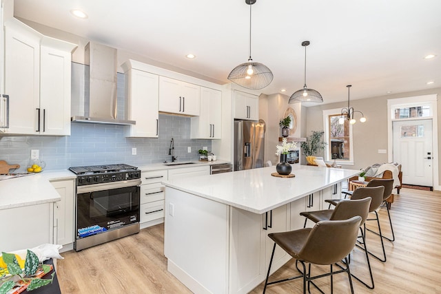 1102 Lee St, Covington, KY 41011 - kitchen with stainless steel appliances, wall chimney exhaust hood, a sink, a kitchen island, and light wood-style flooring