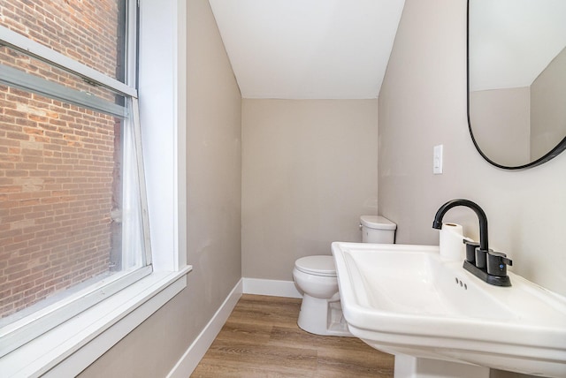 1102 Lee St, Covington, KY 41011 - bathroom with toilet, wood finished floors, baseboards, brick wall, and a sink