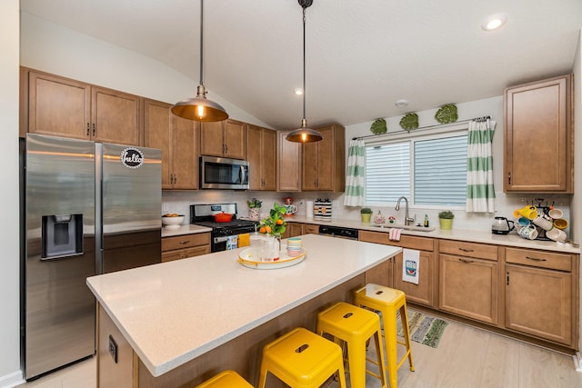 kitchen with appliances with stainless steel finishes, a sink, lofted ceiling, a kitchen breakfast bar, and a kitchen island