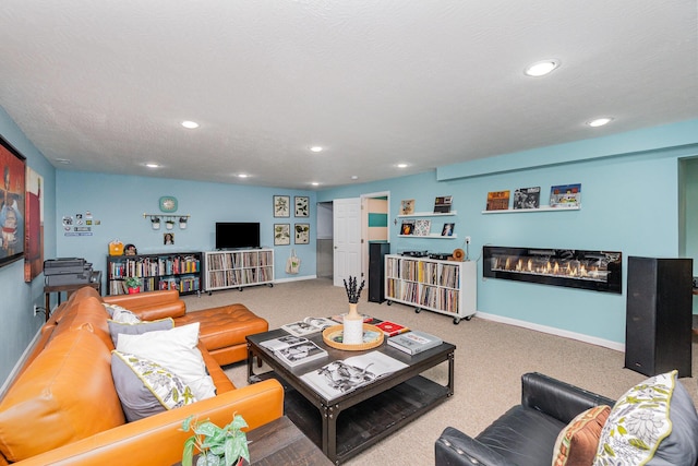 carpeted living area with a glass covered fireplace, recessed lighting, and baseboards