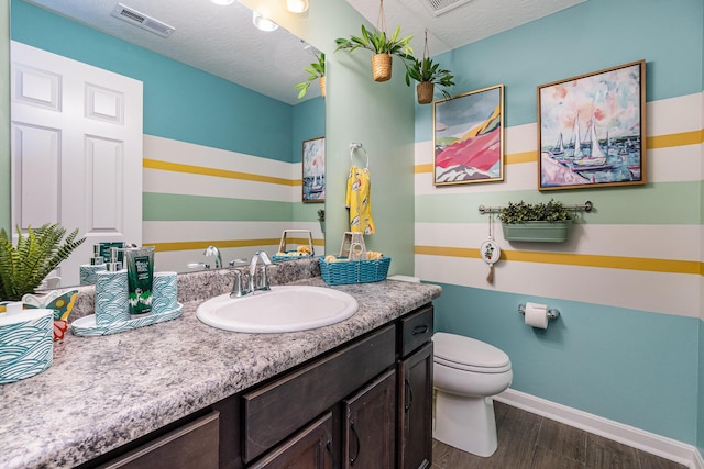 bathroom featuring wood finished floors, vanity, baseboards, and toilet