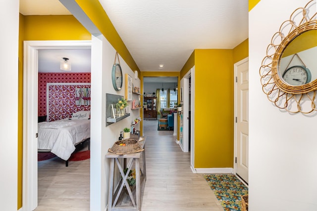 hall featuring light wood-type flooring and baseboards