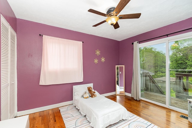 bedroom featuring access to exterior, baseboards, wood finished floors, and a ceiling fan
