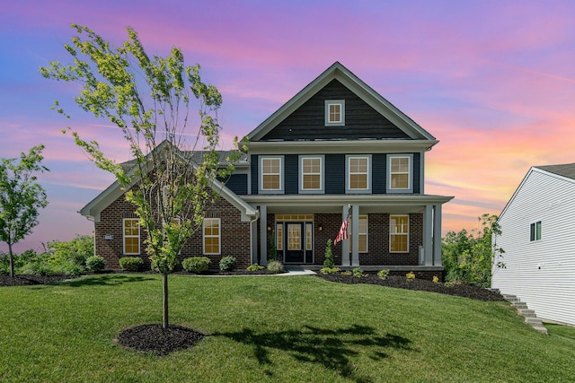view of front of property with brick siding, a lawn, and covered porch