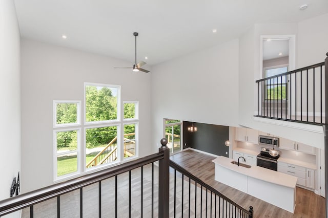 stairway with wood finished floors, plenty of natural light, a ceiling fan, recessed lighting, and a towering ceiling