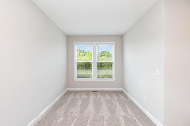 spare room with baseboards and light carpet