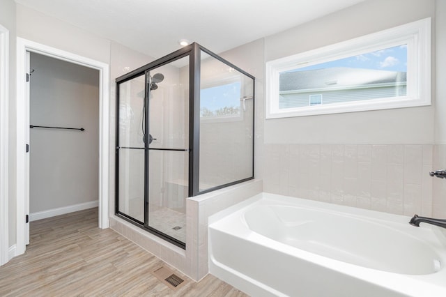 full bath featuring a stall shower, a bath, and wood finished floors