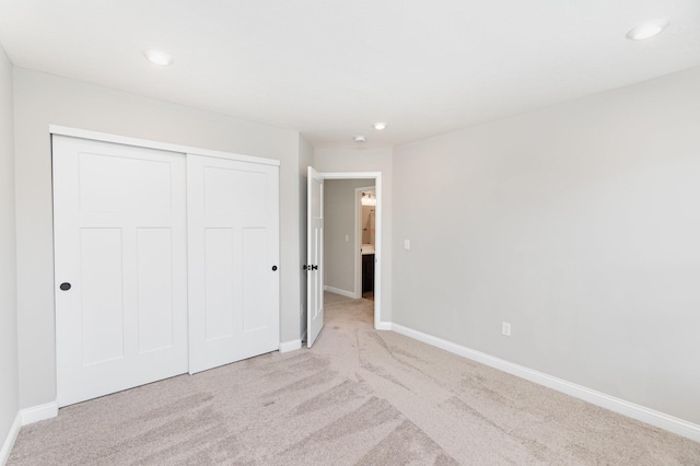 unfurnished bedroom featuring baseboards, light colored carpet, a closet, and recessed lighting