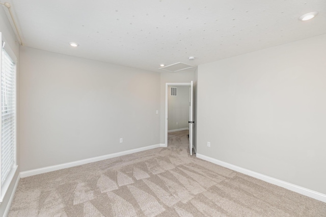 spare room featuring light colored carpet, recessed lighting, and baseboards