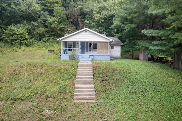 bungalow-style home with a porch, stairway, a front lawn, and a view of trees