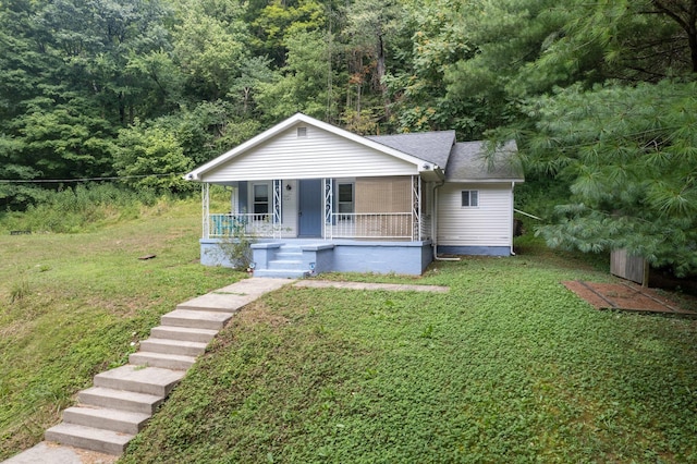 bungalow-style house with covered porch, a front lawn, and a view of trees