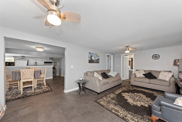 living area featuring a ceiling fan and baseboards