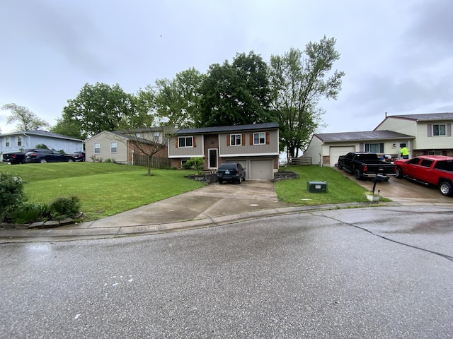 raised ranch featuring concrete driveway and a front yard