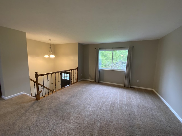 unfurnished room featuring carpet, a chandelier, and baseboards