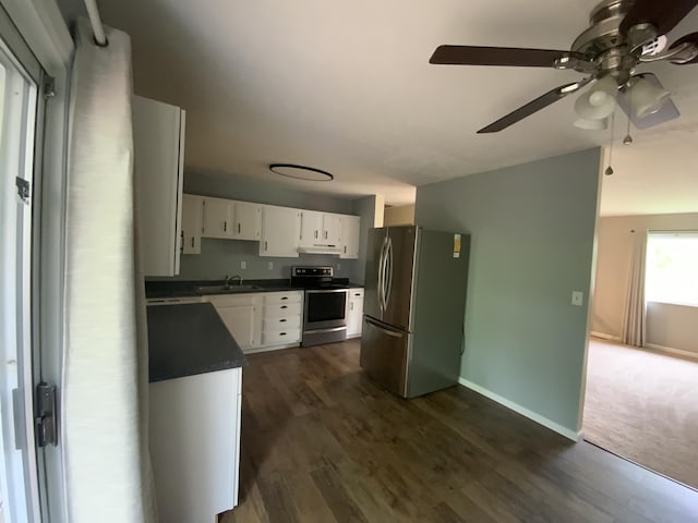 kitchen featuring appliances with stainless steel finishes, dark countertops, a sink, a ceiling fan, and white cabinets