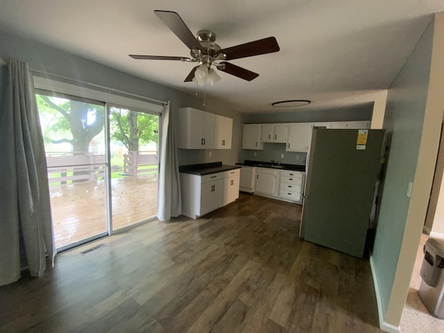 kitchen with freestanding refrigerator, dark countertops, dark wood finished floors, and white cabinets