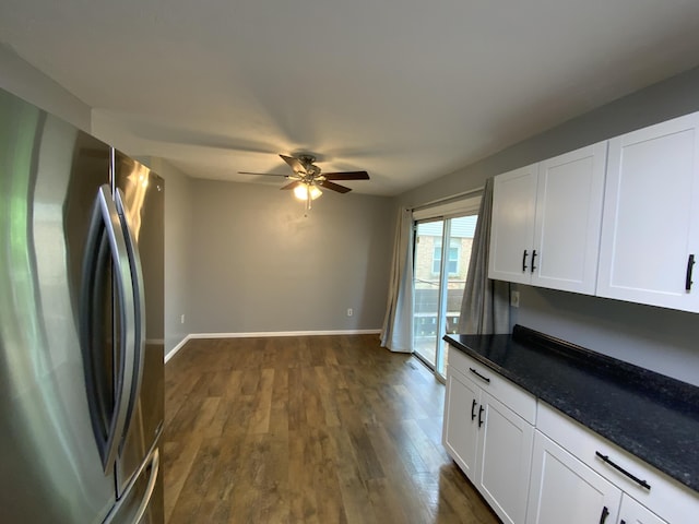 kitchen with freestanding refrigerator, ceiling fan, dark wood-type flooring, white cabinets, and dark stone countertops