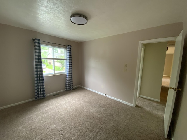 spare room with carpet floors, baseboards, and a textured ceiling