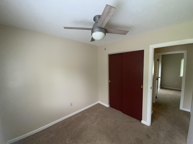 unfurnished bedroom featuring carpet floors, a closet, baseboards, and ceiling fan