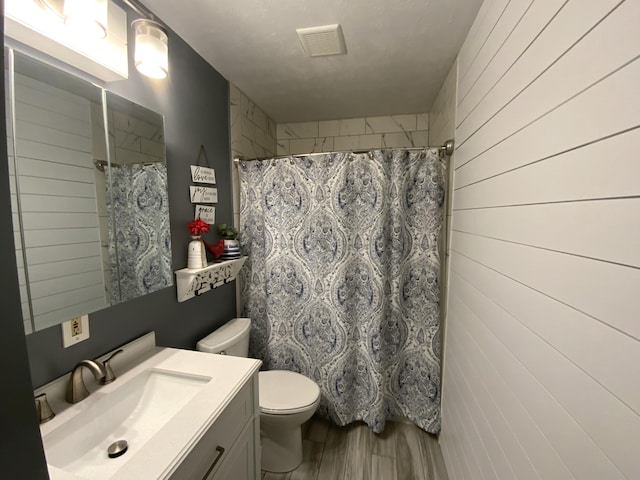 full bathroom featuring vanity, toilet, wooden walls, curtained shower, and wood finished floors