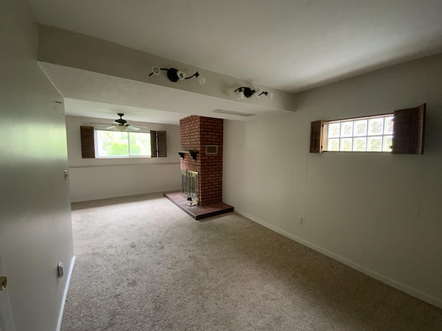 unfurnished room with carpet, a fireplace, ceiling fan, and baseboards