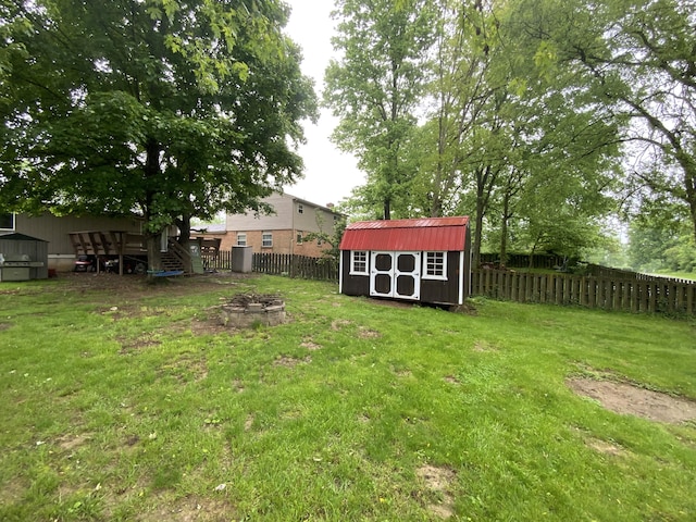 view of yard featuring a storage shed, an outdoor structure, an outdoor fire pit, and a wooden deck
