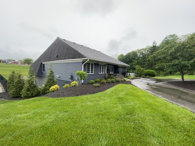 view of home's exterior featuring roof with shingles and a yard
