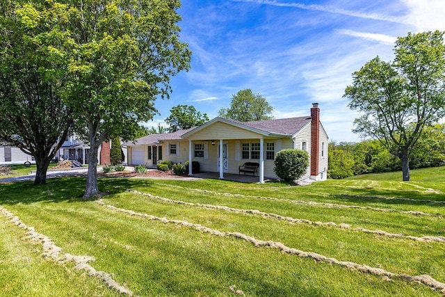 view of front facade with a garage, a chimney, a front lawn, and driveway