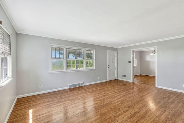 unfurnished room with crown molding, wood finished floors, and baseboards