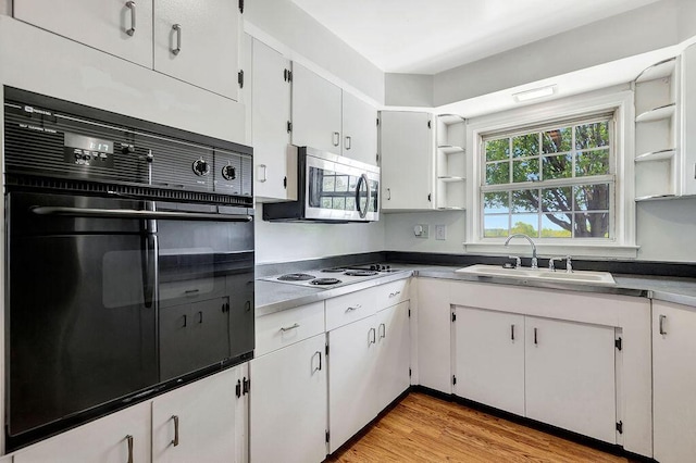 kitchen with a sink, open shelves, oven, stainless steel microwave, and white cabinets