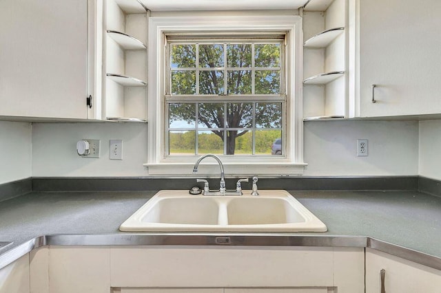 kitchen featuring a sink, open shelves, white cabinets, and dark countertops