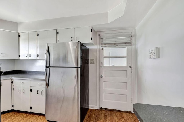 kitchen with freestanding refrigerator, light wood-type flooring, and white cabinets