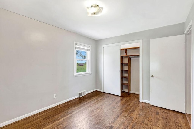 unfurnished bedroom featuring wood finished floors, baseboards, and a closet