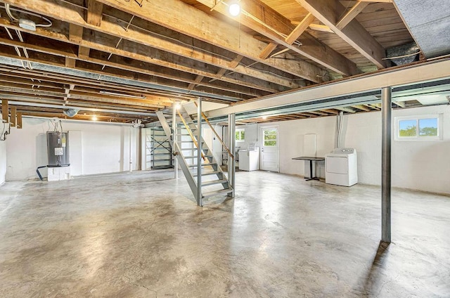 below grade area featuring stairs, water heater, and separate washer and dryer