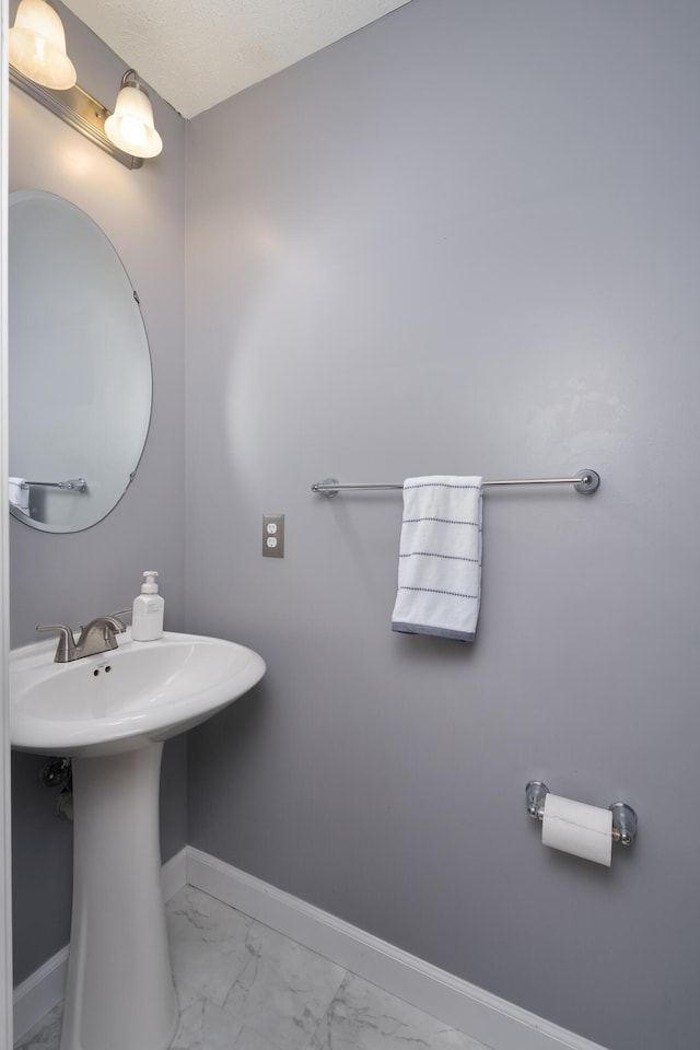 bathroom with marble finish floors, baseboards, and a sink