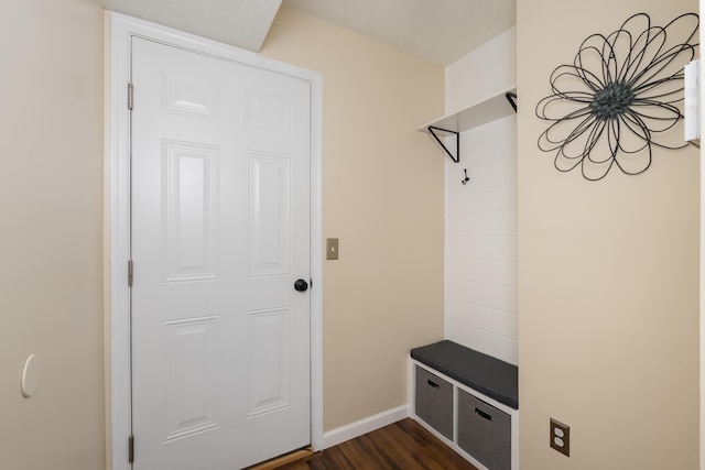 mudroom with dark wood finished floors and baseboards