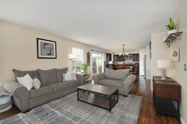 living area featuring a chandelier, dark wood-type flooring, and baseboards