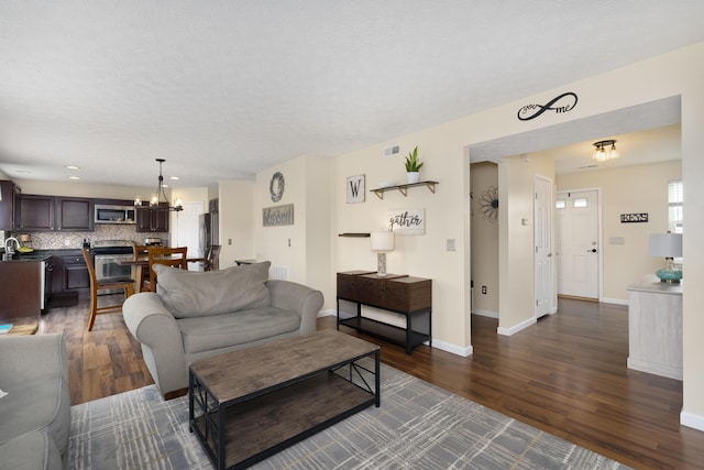 living area with dark wood finished floors, a chandelier, baseboards, a textured ceiling, and recessed lighting