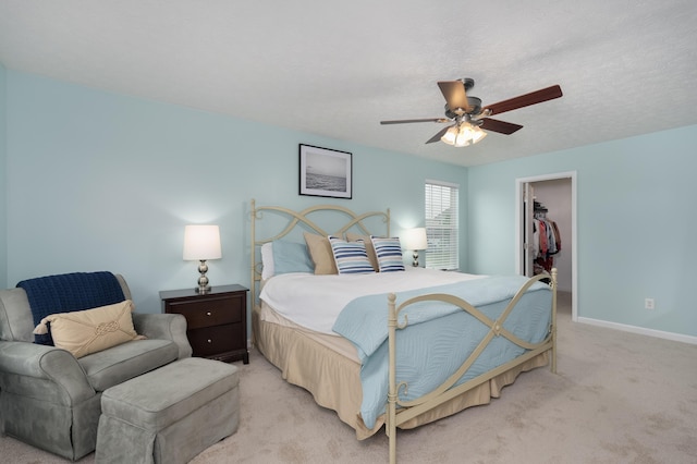 bedroom with light colored carpet, a spacious closet, baseboards, a closet, and ceiling fan