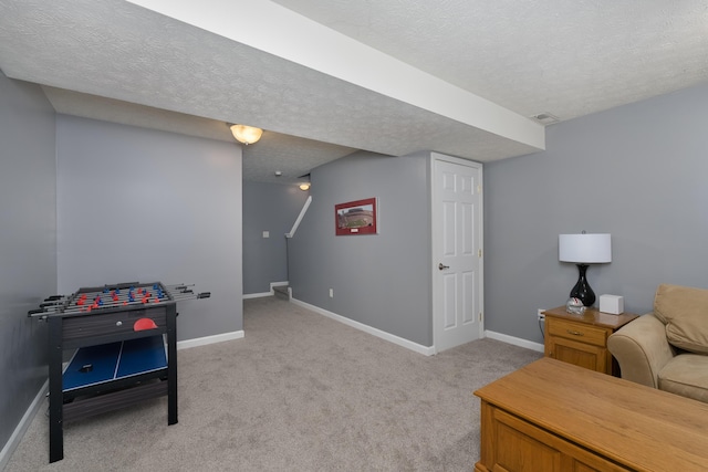 playroom with a textured ceiling, baseboards, and light colored carpet