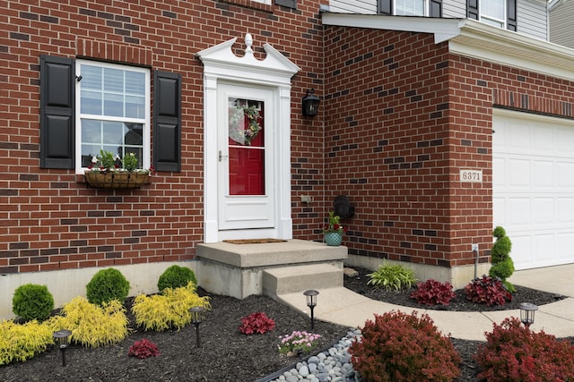 view of exterior entry featuring brick siding and a garage