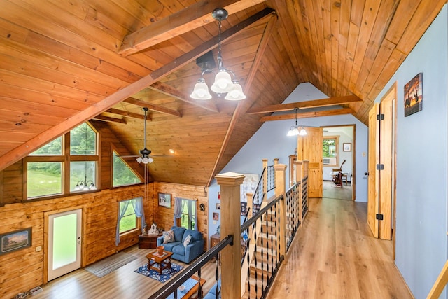 corridor with wood ceiling, a chandelier, an upstairs landing, light wood-type flooring, and wooden walls